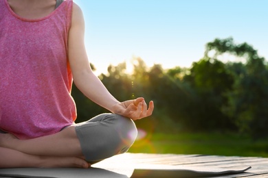 Photo of Young woman practicing yoga outdoors, closeup. Zen meditation