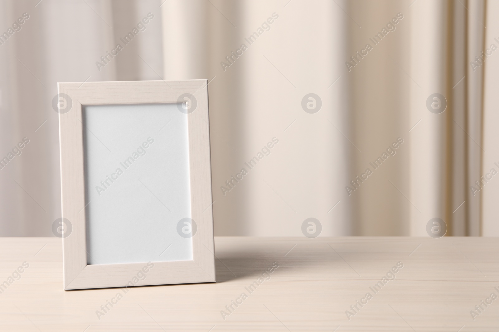 Photo of Empty square frame on white wooden table indoors, space for text