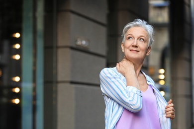 Photo of Happy mature woman on city street, space for text. Smart aging