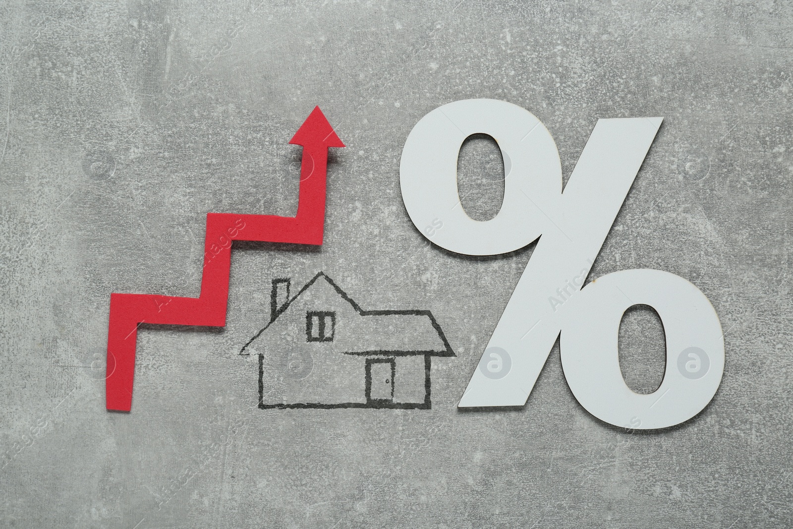 Image of Mortgage rate rising illustrated by upward arrow, house icon and percent sign on gray background, top view