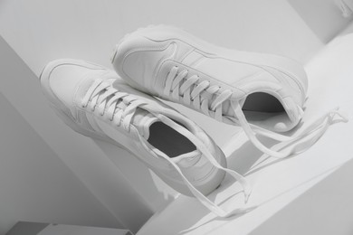 Photo of Stylish presentation of trendy sneakers on white background