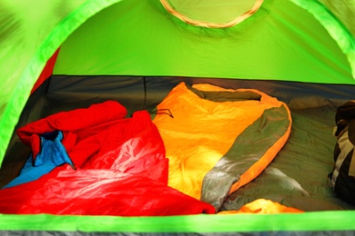 Photo of Camping tent with bright sleeping bags outdoors