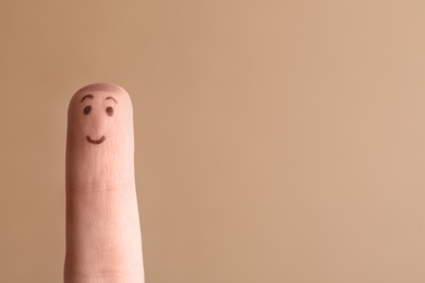 Finger with drawing of happy face on brown background. Space for text