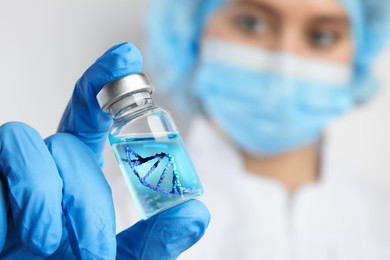 Image of Genetics research. Scientist holding vial with liquid and illustration of DNA structure, selective focus