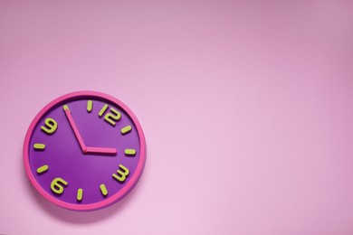 Photo of Stylish round clock on pale pink background, top view with space for text. Interior element