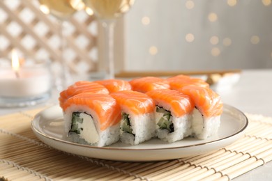 Photo of Tasty sushi rolls on table against blurred lights, closeup