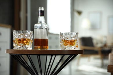 Glasses and bottle of whiskey on table indoors