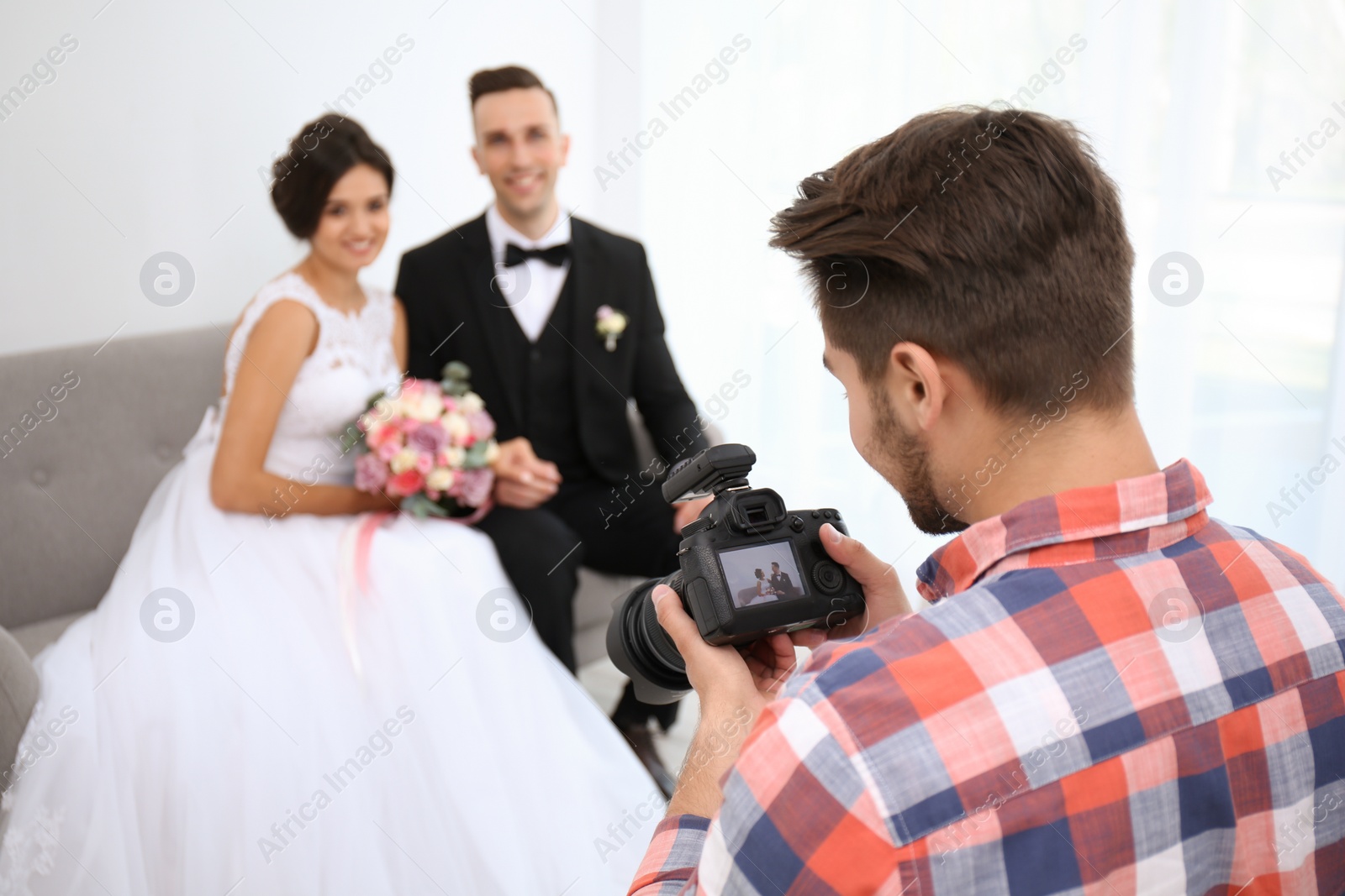 Photo of Professional photographer with camera and wedding couple in studio