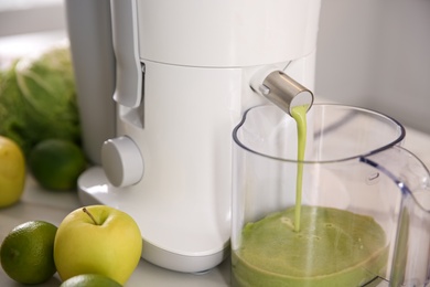 Photo of Modern juicer and fresh fruits on table in kitchen, closeup