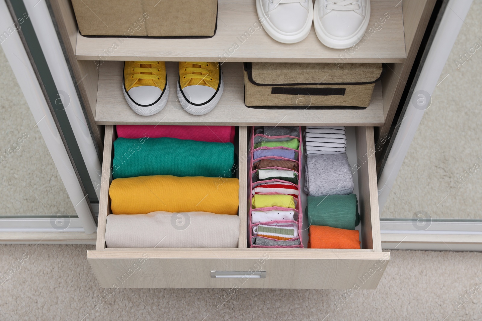 Photo of Wardrobe with organized clothes and shoes indoors, above view. Vertical storage