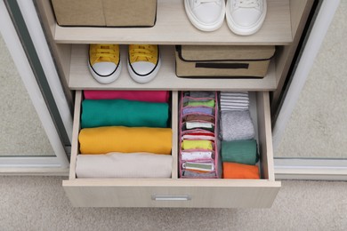 Photo of Wardrobe with organized clothes and shoes indoors, above view. Vertical storage