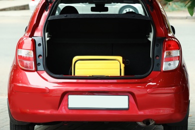 Photo of Yellow suitcase in car trunk outdoors, closeup
