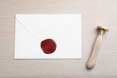 Photo of Envelope with wax seal and stamp on white wooden table