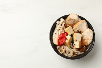 Photo of Bowl of delicious ramen on white table, top view with space for text. Noodle soup