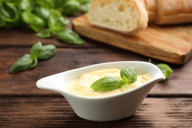 Photo of Tasty sauce with basil leaves in gravy boat on wooden table