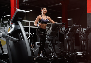Young woman working out on elliptical trainer in modern gym