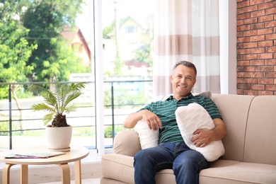 Photo of Man relaxing on sofa with comfortable pillows at home