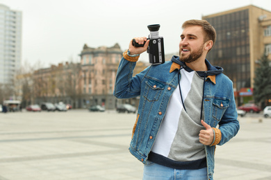 Photo of Young man with vintage video camera on city street