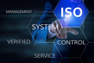 Image of Businessman pointing at virtual icon with text ISO on dark background, closeup 