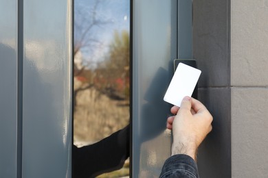 Photo of Man opening magnetic door lock with key card outdoors, closeup