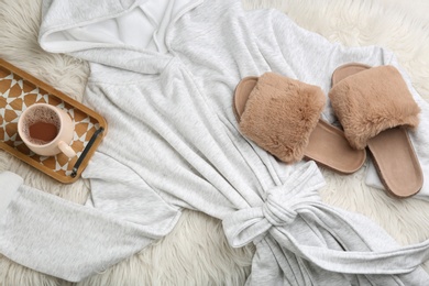 Photo of Pair of fluffy slippers, bath robe and coffee on fuzzy carpet, flat lay. Comfortable home outfit