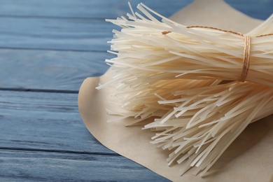 Photo of Raw rice noodles on wooden table, closeup. Space for text