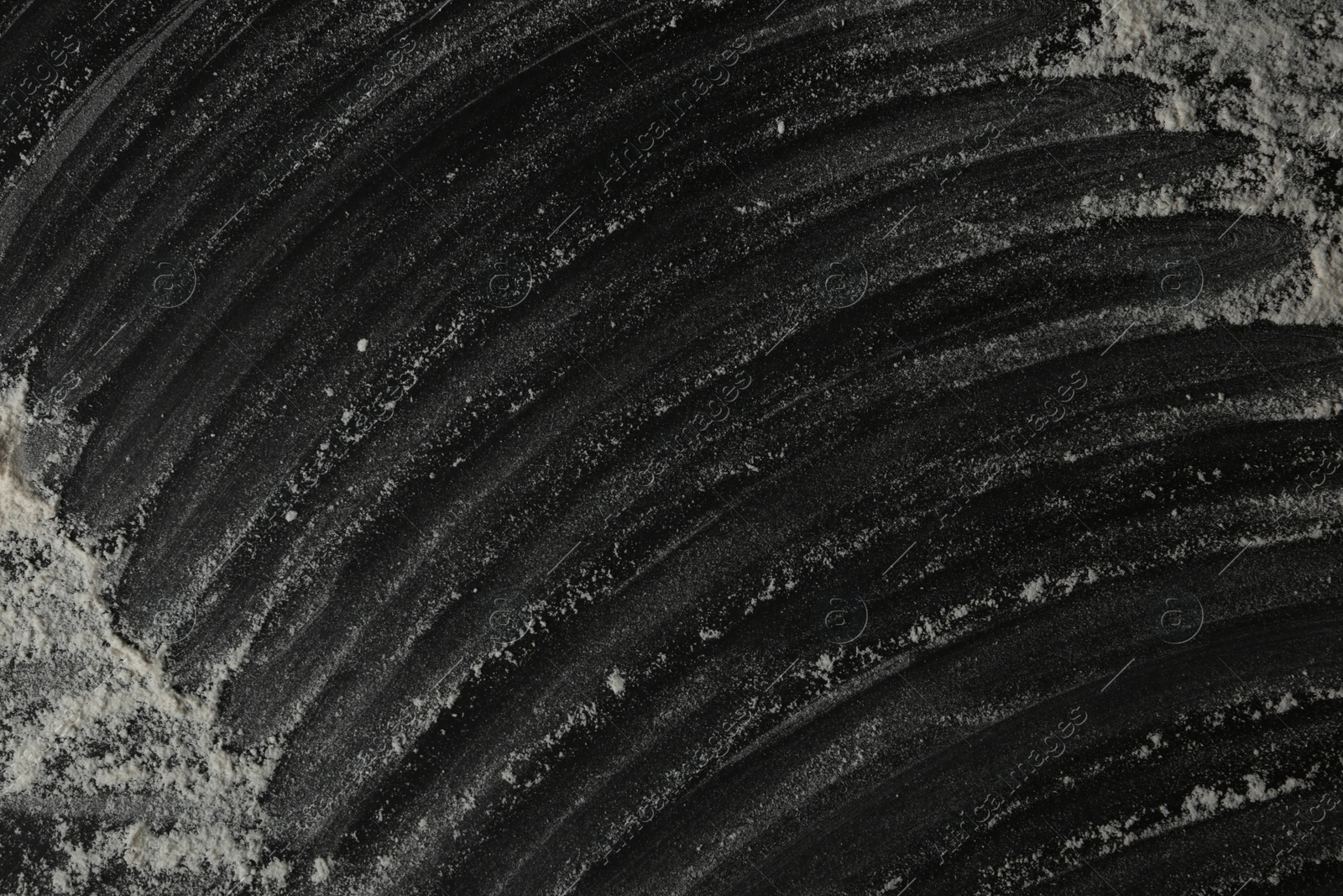 Photo of White flour on black table, top view. Space for text