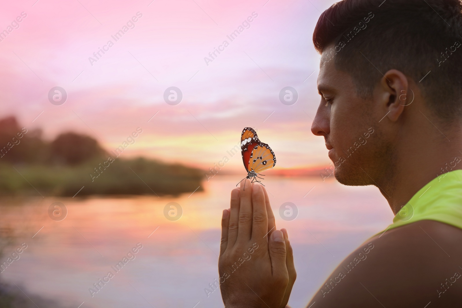 Image of Man meditating near river at sunset. Space for text