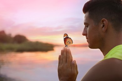 Man meditating near river at sunset. Space for text