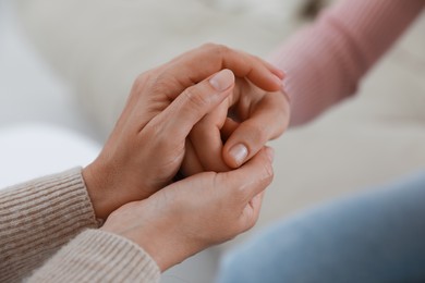 Psychotherapist holding patient's hand indoors, closeup view