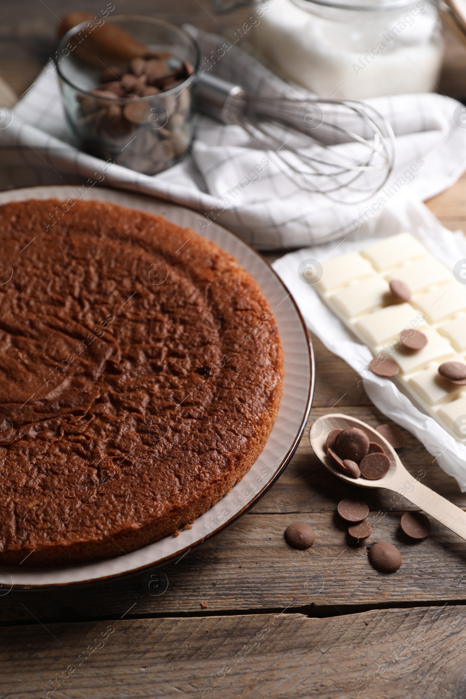 Photo of Delicious homemade sponge cake and different kinds of chocolate on wooden table