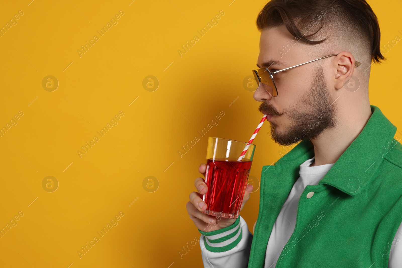 Photo of Handsome young man drinking juice on yellow background. Space for text