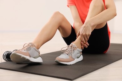 Photo of Woman suffering from leg pain on exercise mat indoors, closeup