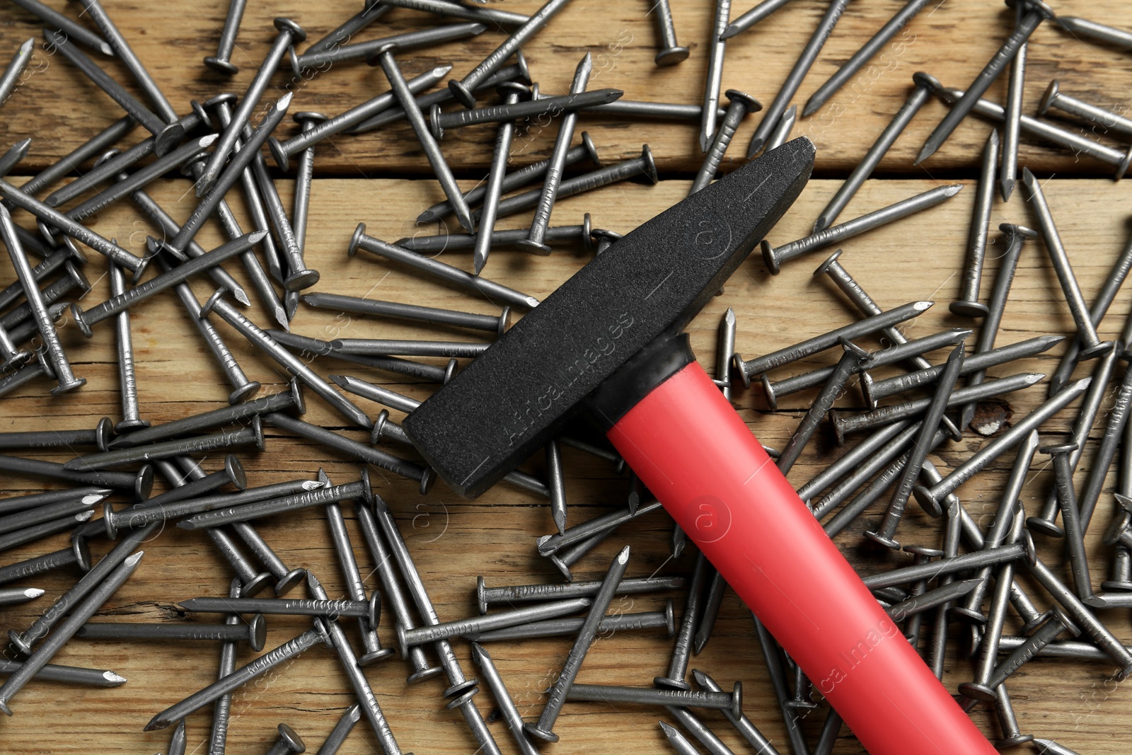 Photo of Hammer and metal nails on wooden table, flat lay