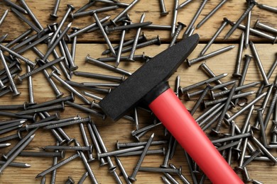 Photo of Hammer and metal nails on wooden table, flat lay