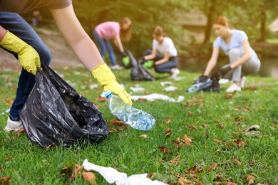 Photo of Man with plastic bag collecting garbage in park, closeup