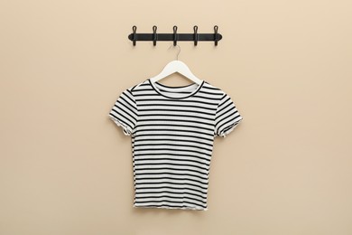 Photo of Hanger with striped t-shirt on beige wall