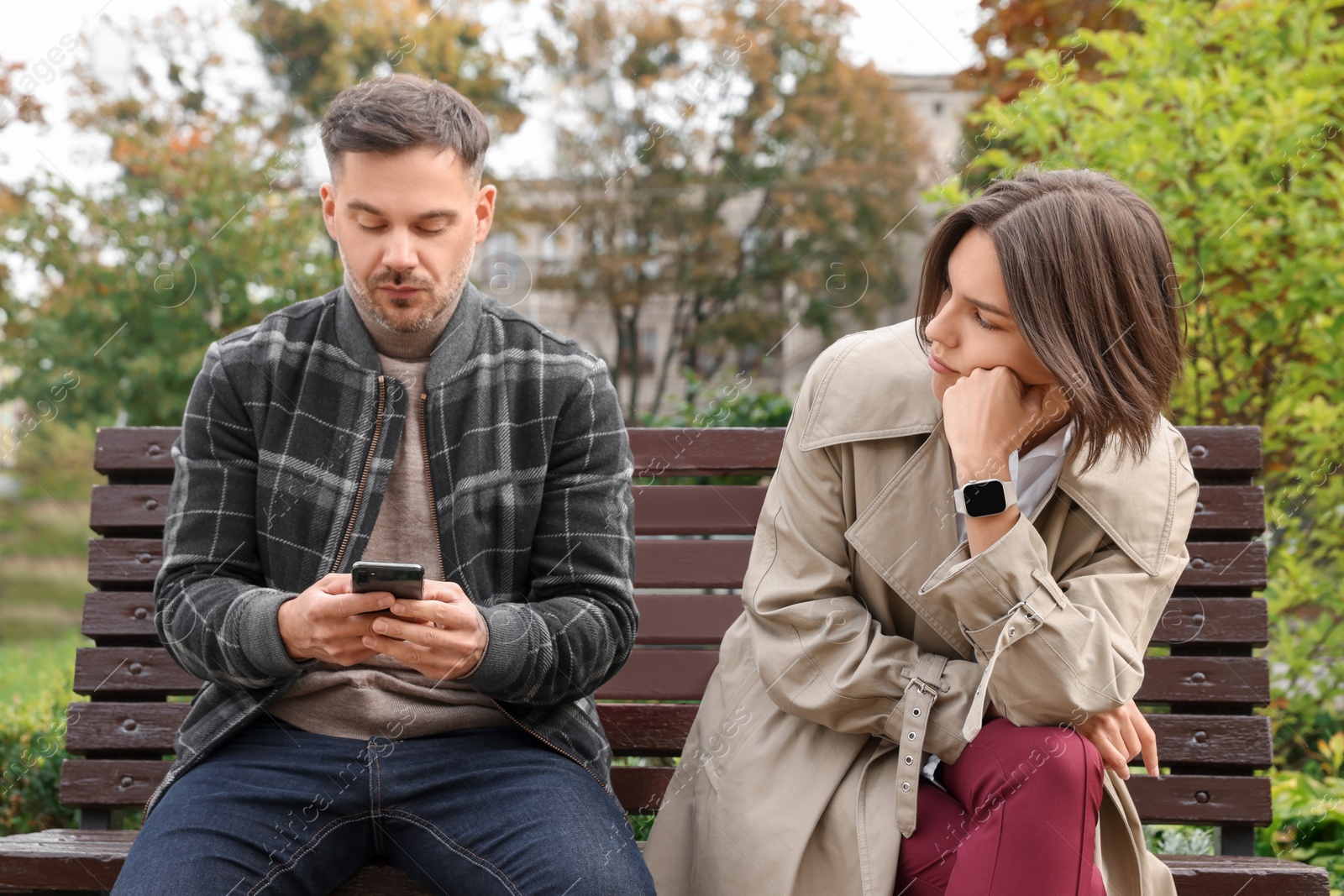 Photo of Man ignoring his girlfriend and using smartphone outdoors. Relationship problems