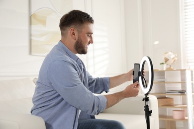 Photo of Blogger preparing for video recording at home. Using ring lamp and smartphone