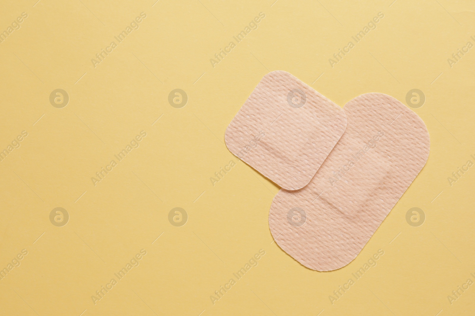 Photo of Different contraceptive patches on yellow background, flat lay. Space for text