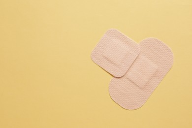 Photo of Different contraceptive patches on yellow background, flat lay. Space for text