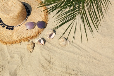 Photo of Straw hat and sunglasses on sand, above view with space for text. Beach accessories