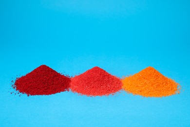 Photo of Heaps of different bright food coloring on light blue background