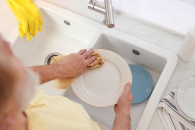 Photo of Man wiping plate in sink, above view