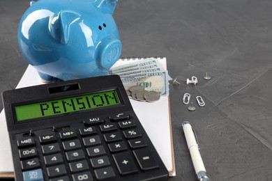 Image of Calculator with word Pension, piggy bank, money and stationery on grey table, closeup