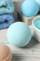 Photo of Beautiful aromatic bath bombs and sea salt on light wooden table, closeup