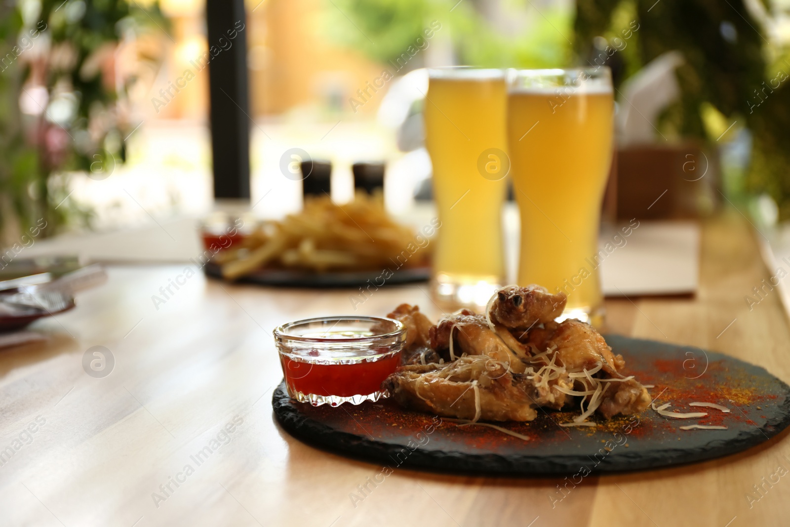 Photo of Delicious hot BBQ wings and beer served on table