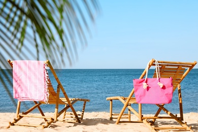 Empty wooden sunbeds and beach accessories on sandy shore