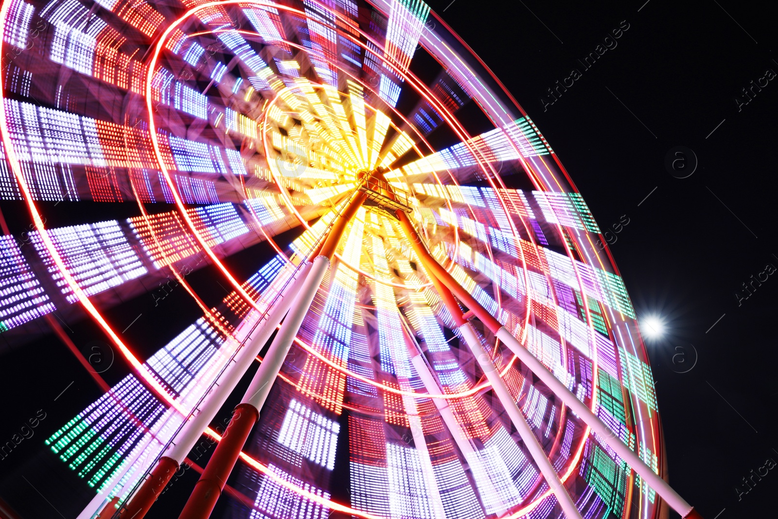 Photo of Beautiful glowing Ferris wheel against dark sky, low angle view