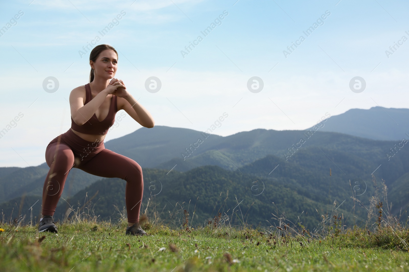 Photo of Young woman doing morning exercise in mountains, space for text